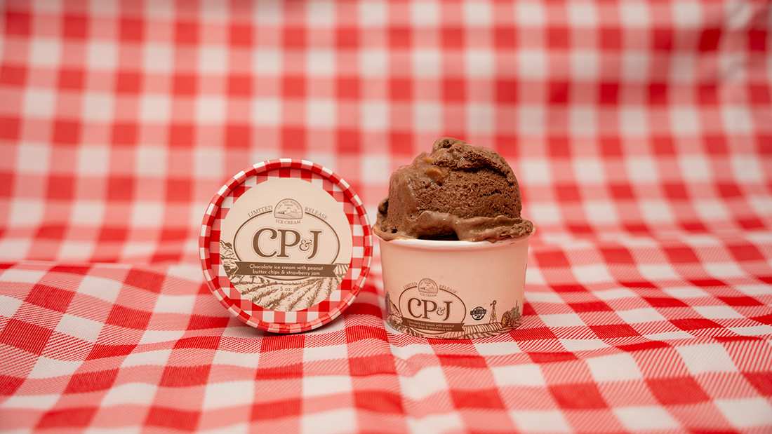 a cup of CP&J on a red and white checkered tablecloth.