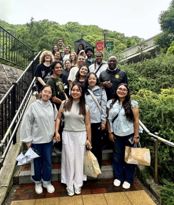 Professor Renford Reese and study abroad students pose for a photo on stairs in Japan. 