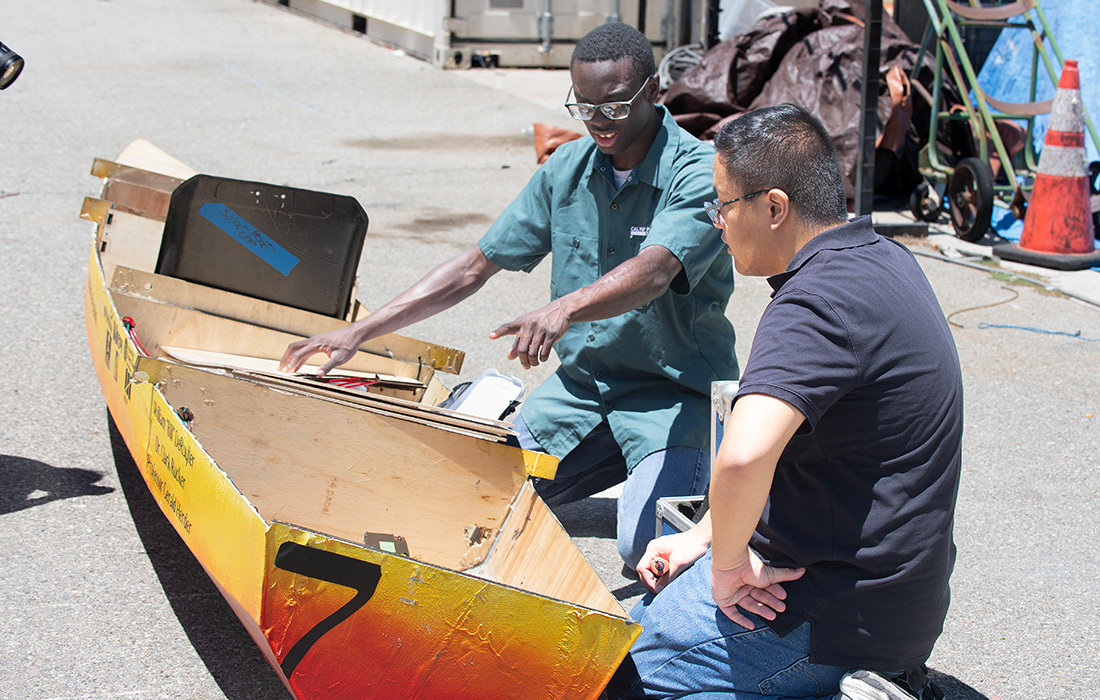 Tristan Obordo and a teammate work on the solar boat.