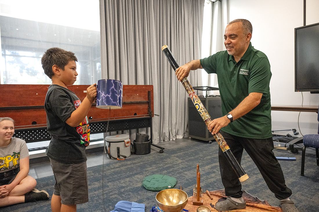 Paul Knopf shows a child how to use a rain stick.
