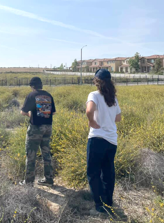 A female and male student in a long grassy field 