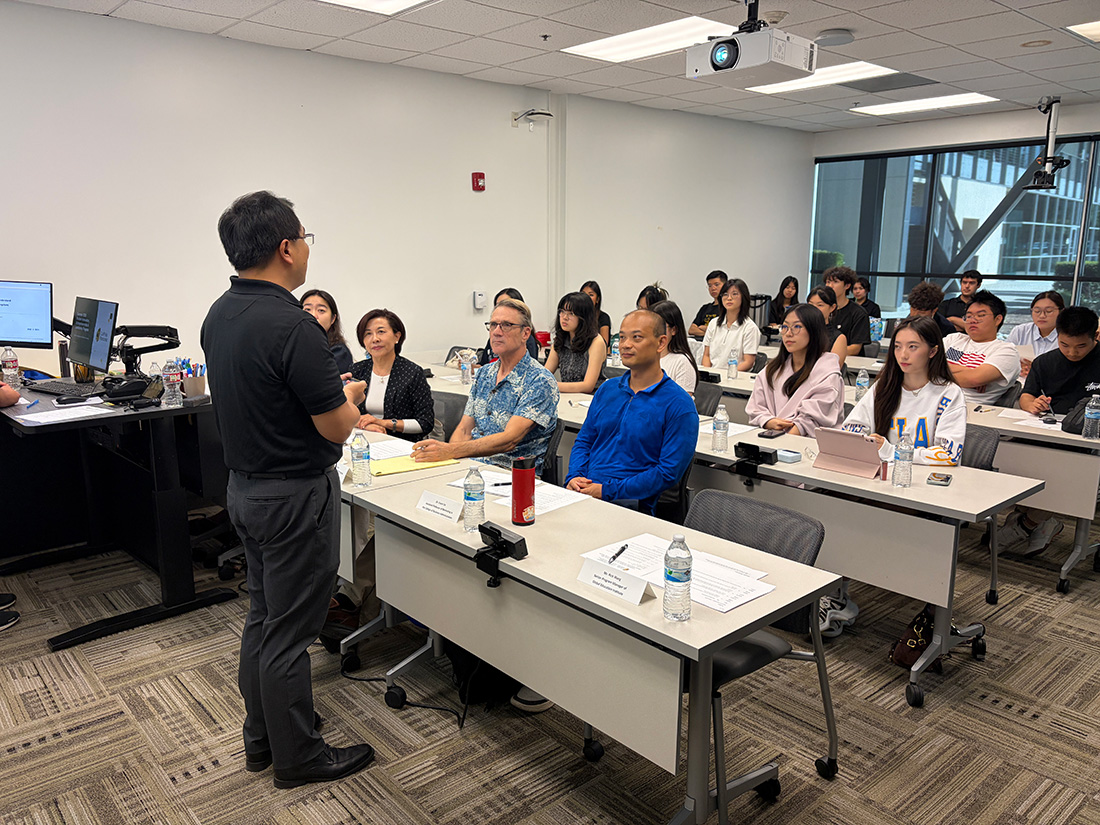 A professor lectures while students listen in a classroom.