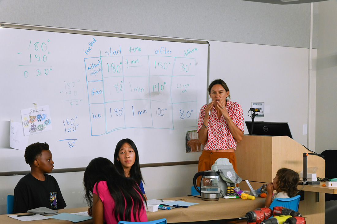 Students sit in a classroom and listen to a female instructor. 