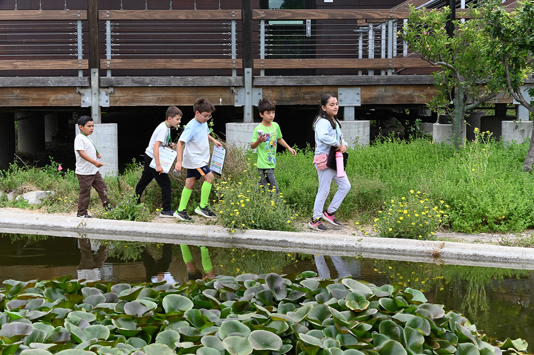 5 students walk by a pond at the Lyle Center at Cal Poly Pomona