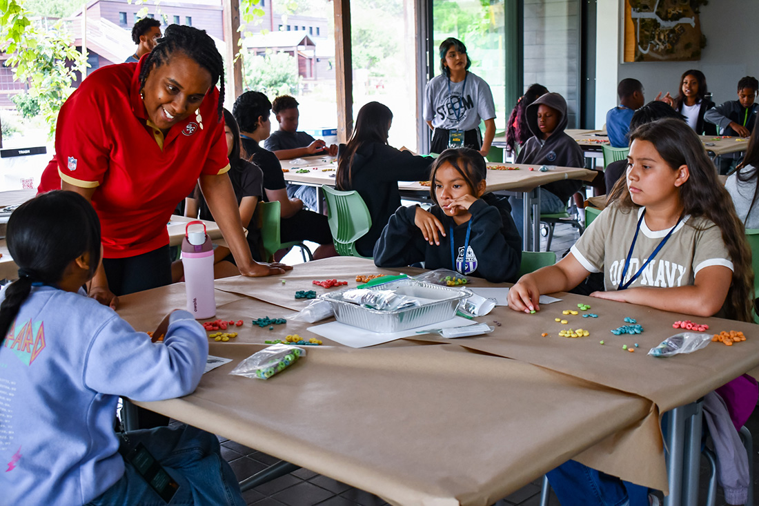 Young students at a table work with piles of cereal. 