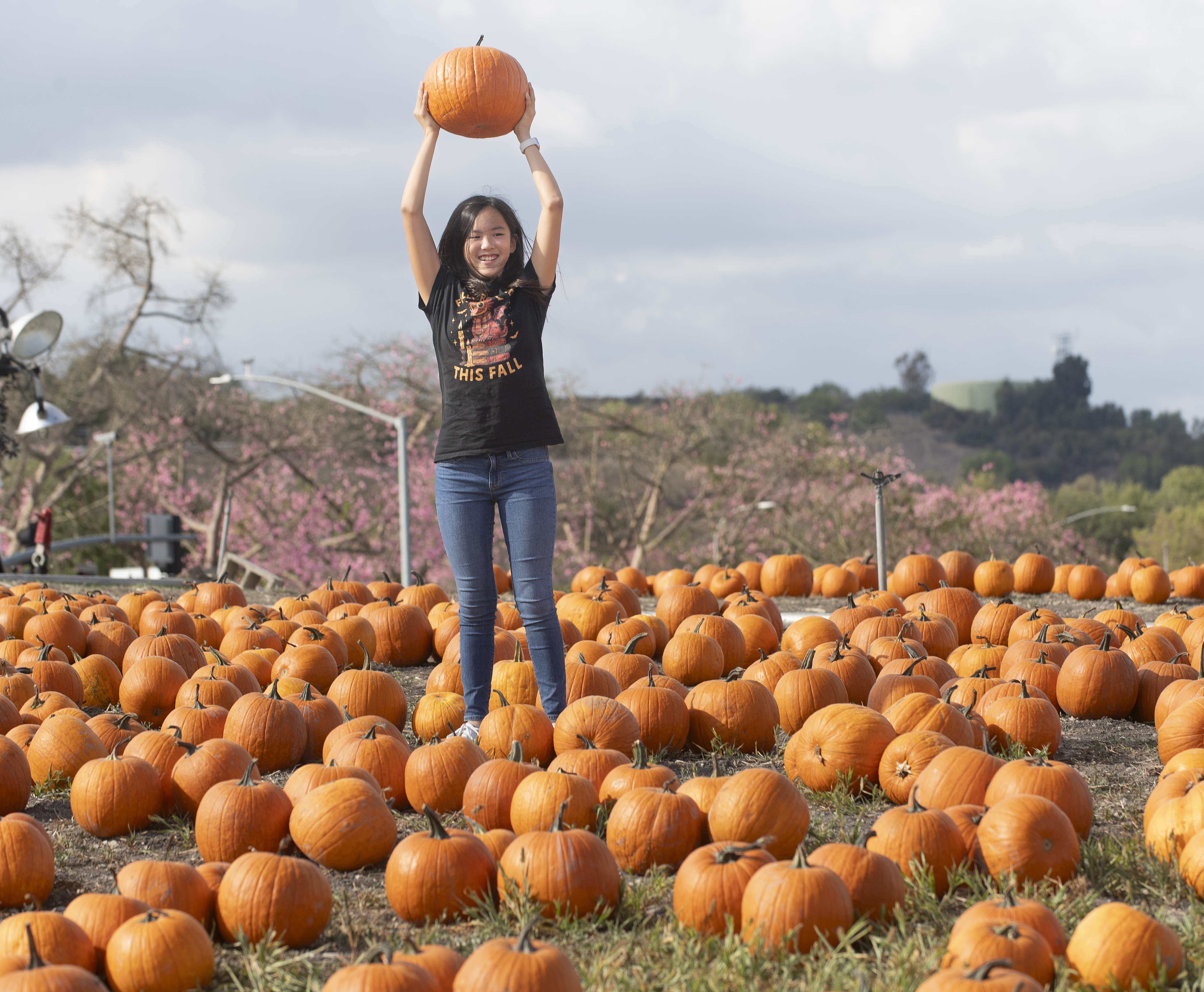 Young girl smiles as she holds a pumpkin over her head during PumpkinFest.