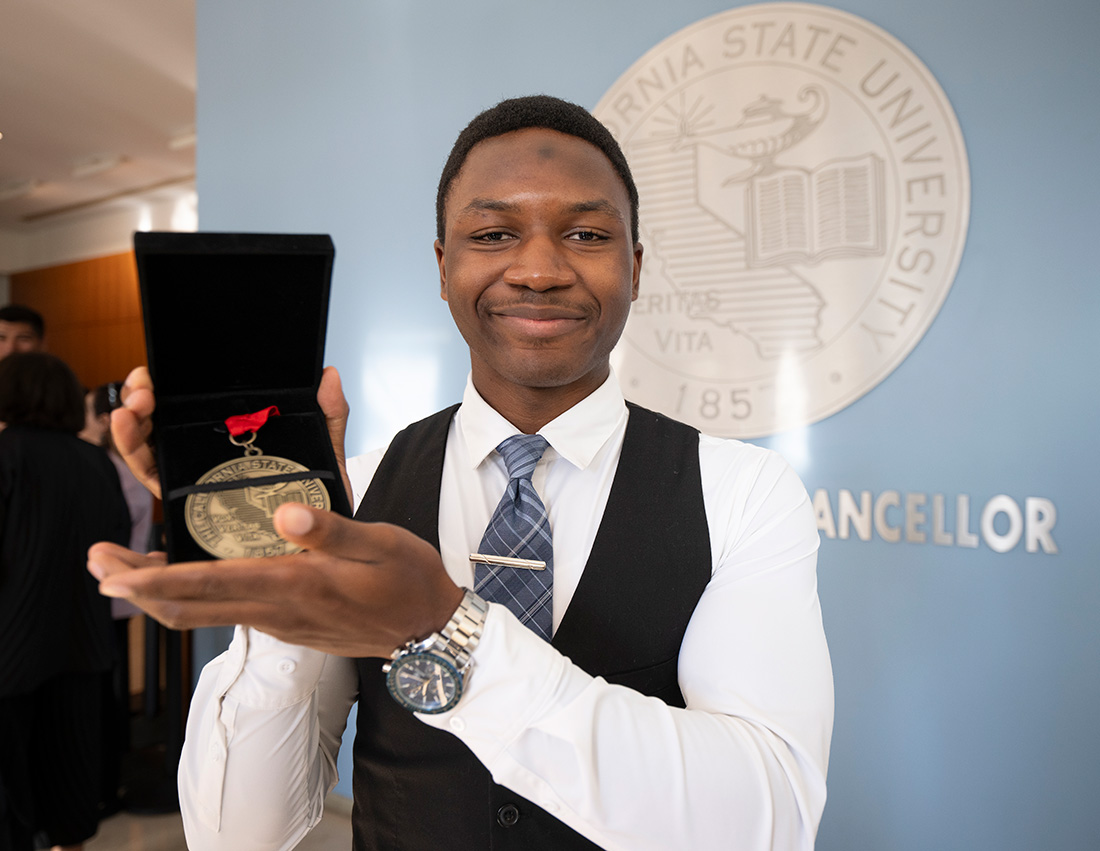 KeJuan Jones smiles while holding his Trustee's award medal.