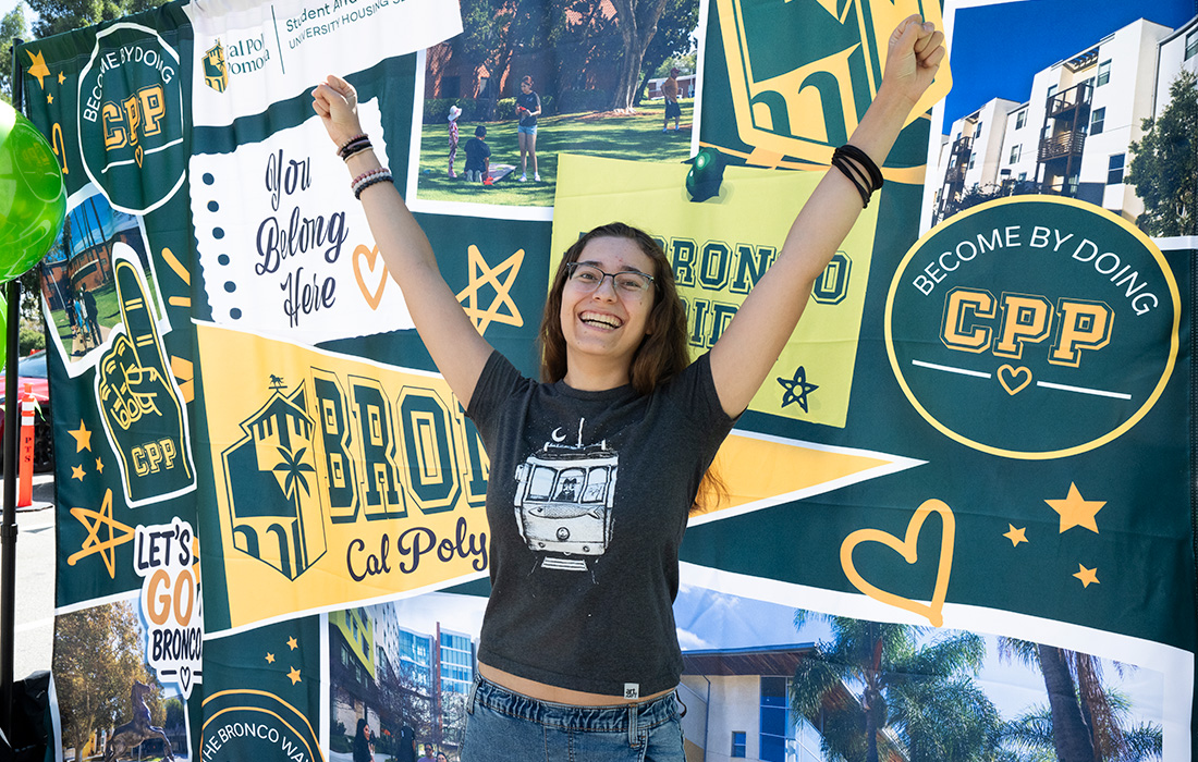 Female student jumps up and smiles during fall 2026 semester move in day.