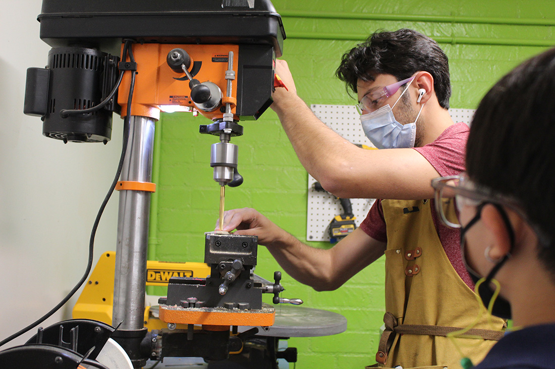 A male student works on a piece of wood that will become a daxophone.