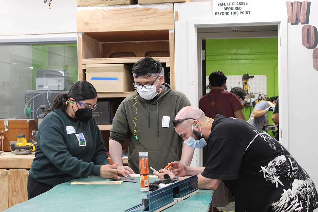 A group of students work at a table to begin construction on a daxophone
