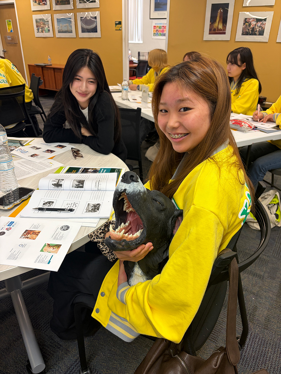 Female Japanese student smiles while holding rubber model of dog head.