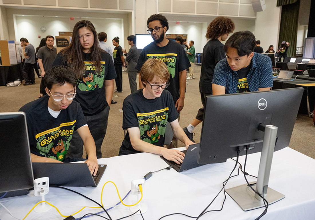 A groupf of student work on laptops while demonstrating during the 2025 Cybersecutiry Fair.