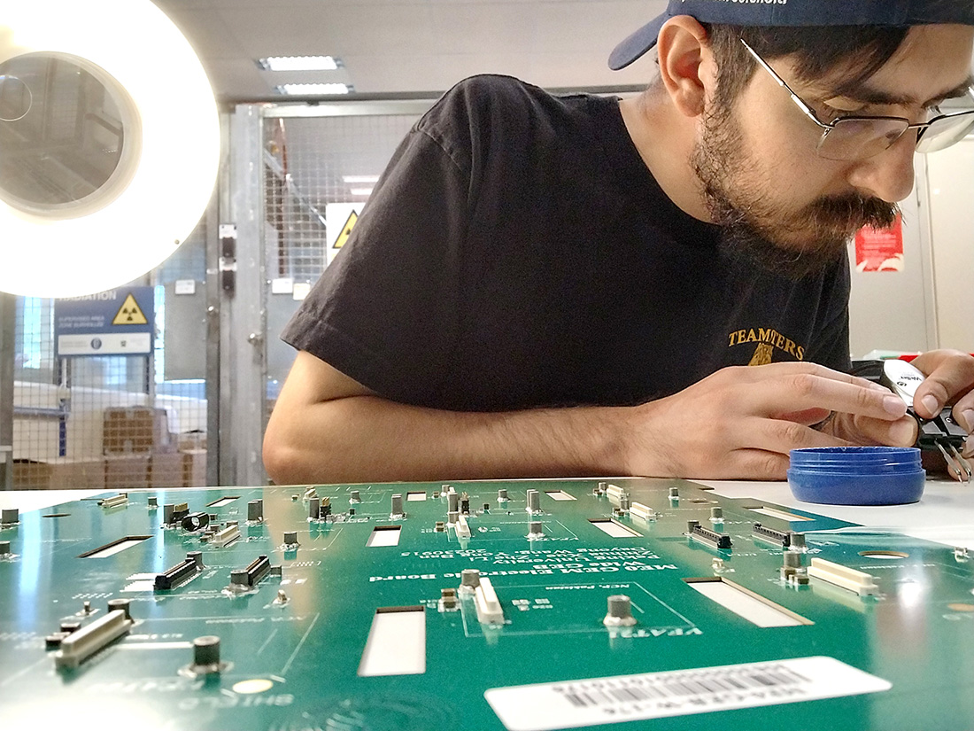 A male student works on a circuit board. 