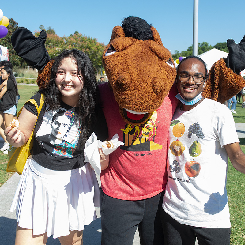Female and Male student hold a hot dog with Billy Bronco during Hot Dog Caper.