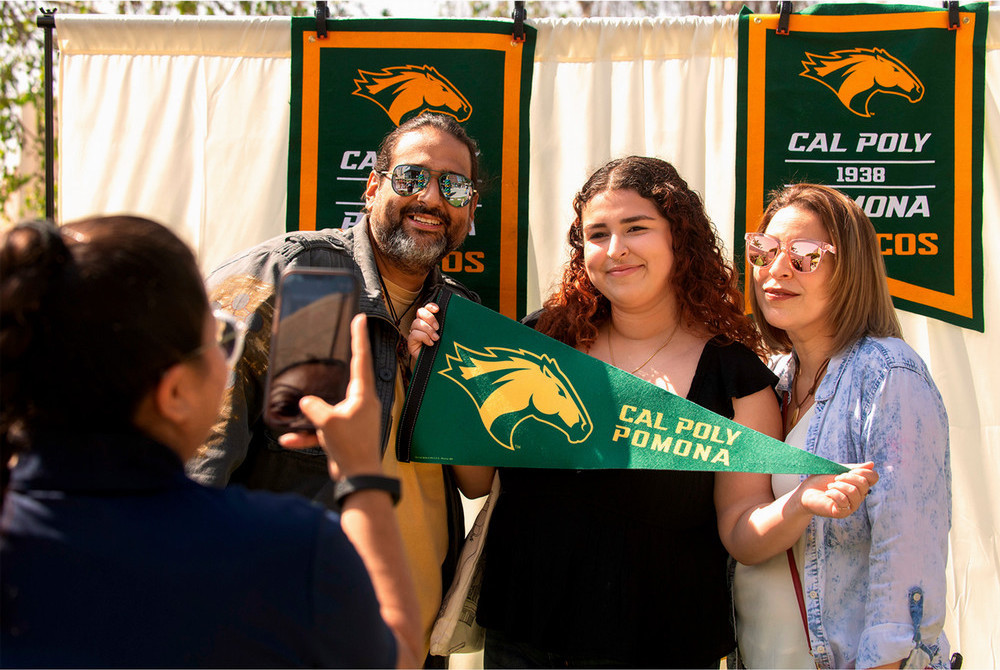 A son and his mother pose for a photo holding a Bronco flag.