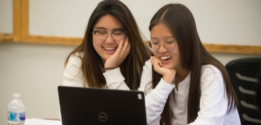 Two students talk while on the computer