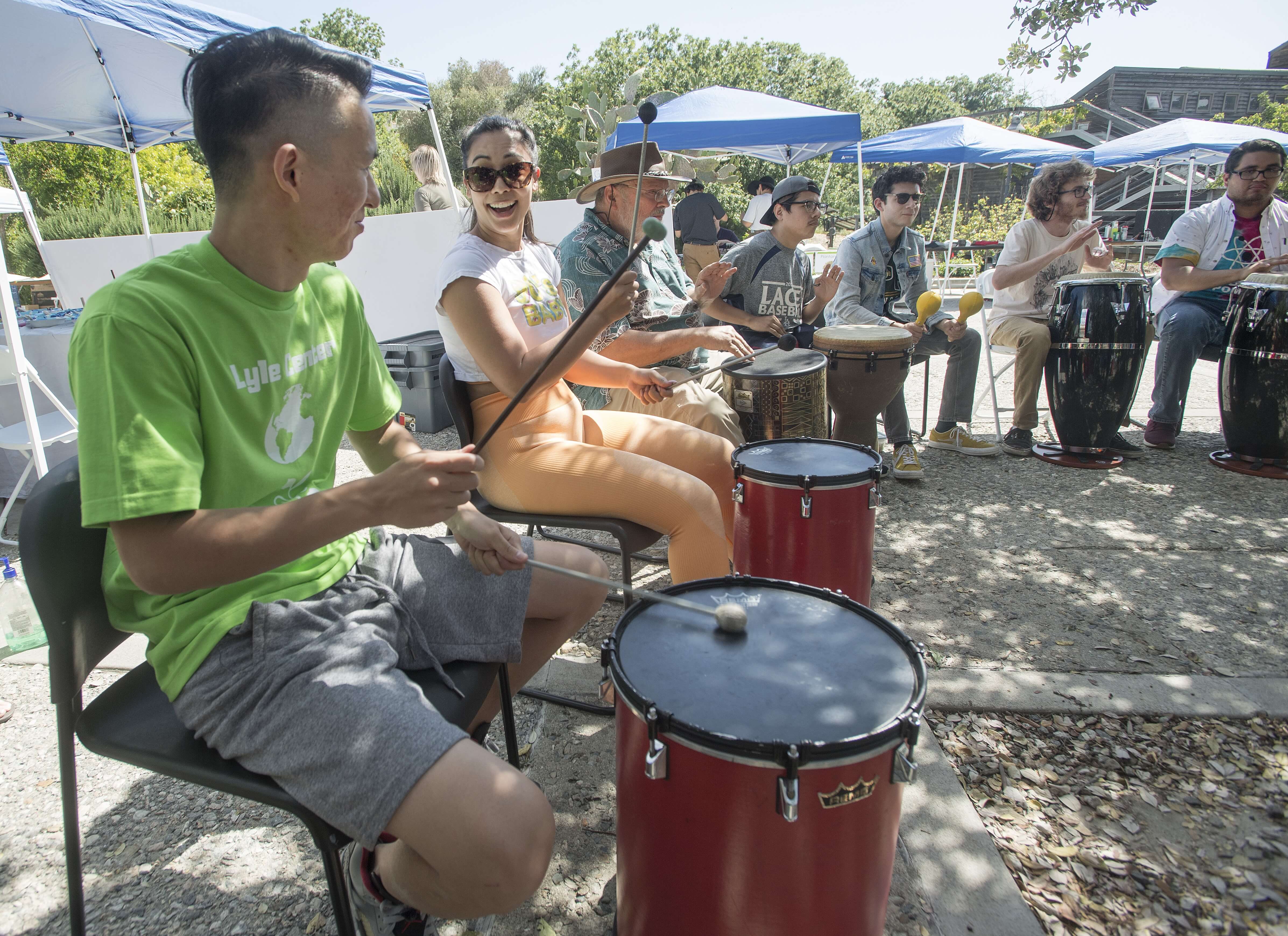 People sat around a circle playing drums outdoors
