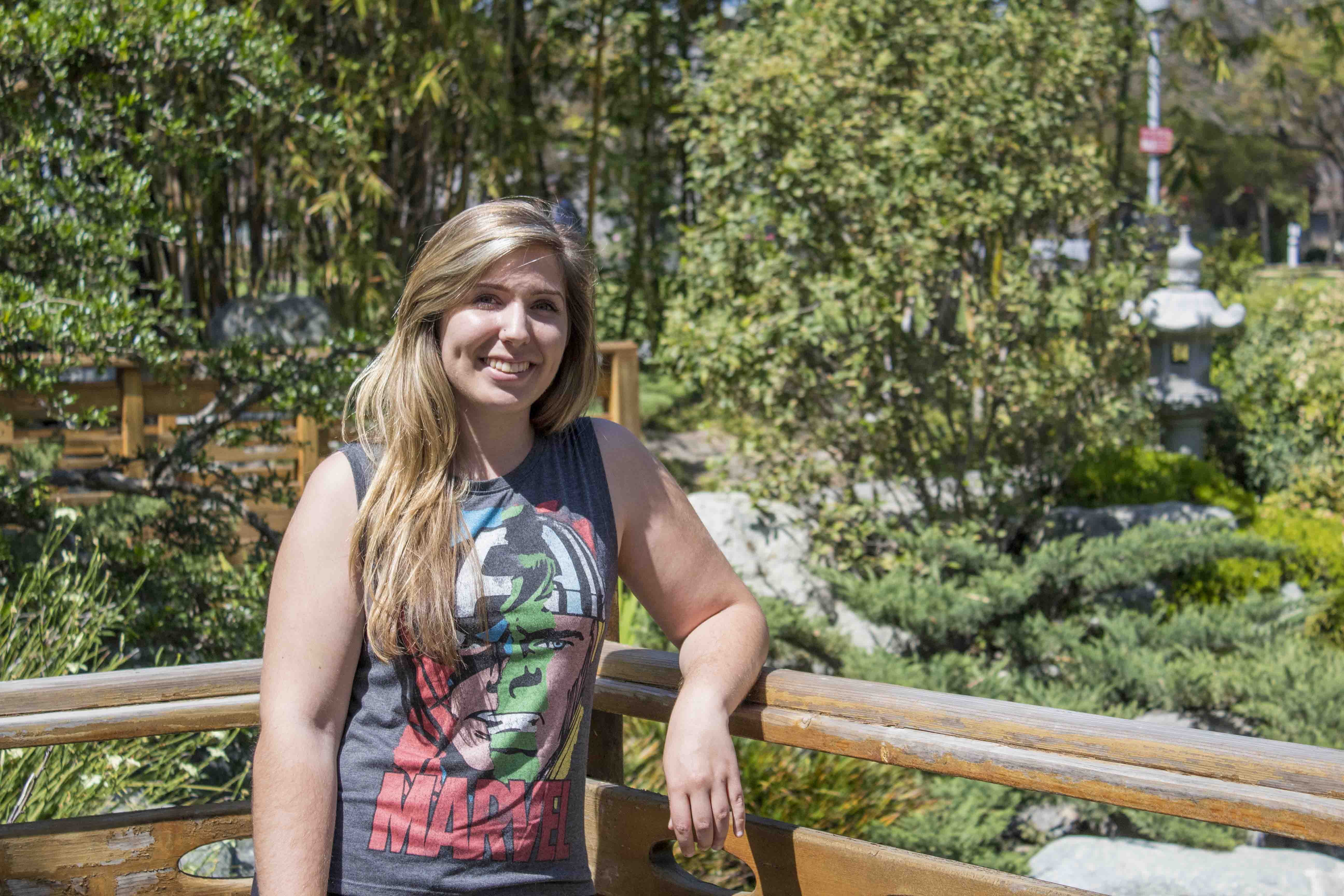 Female student in a garden, with her right arm resting on a fences