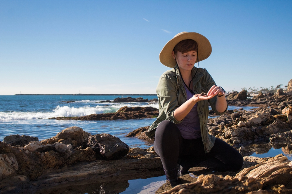 Female students at a marine reserve, examining rocks in her hand