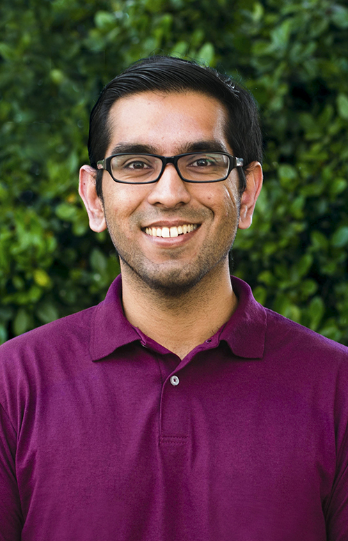 Male student in a burgundy shirt smiling confidently