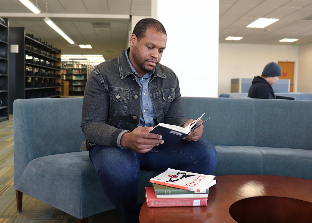 Image of Jeremy sitting in a library and reading a book