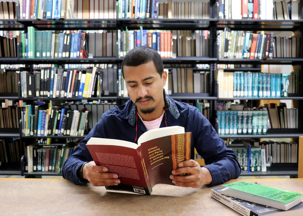 Image of Randell sitting down at the library while reading a book