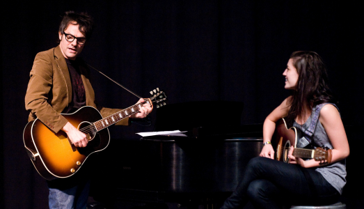 Two musicians playing guitars together.