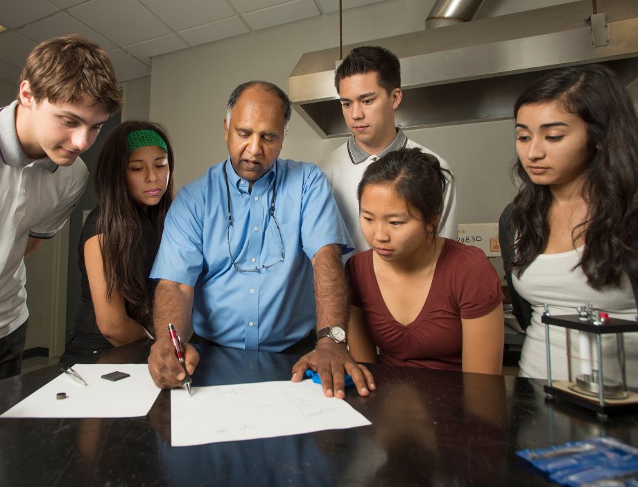 A group of students an professor going over a project together.