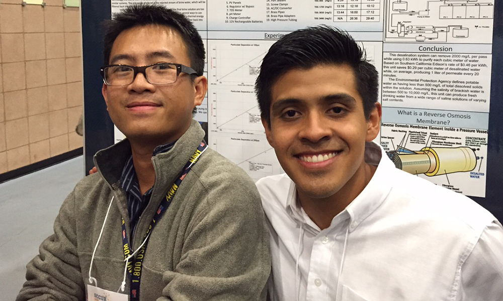 Two students posing in front of their poster presentation at research conference