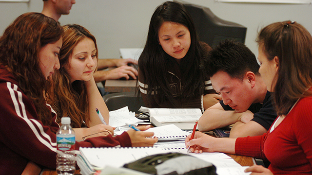 Students gathered around table, working together with mentor