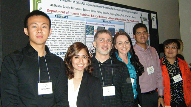 Group of research students posing in front of their research with their mentor