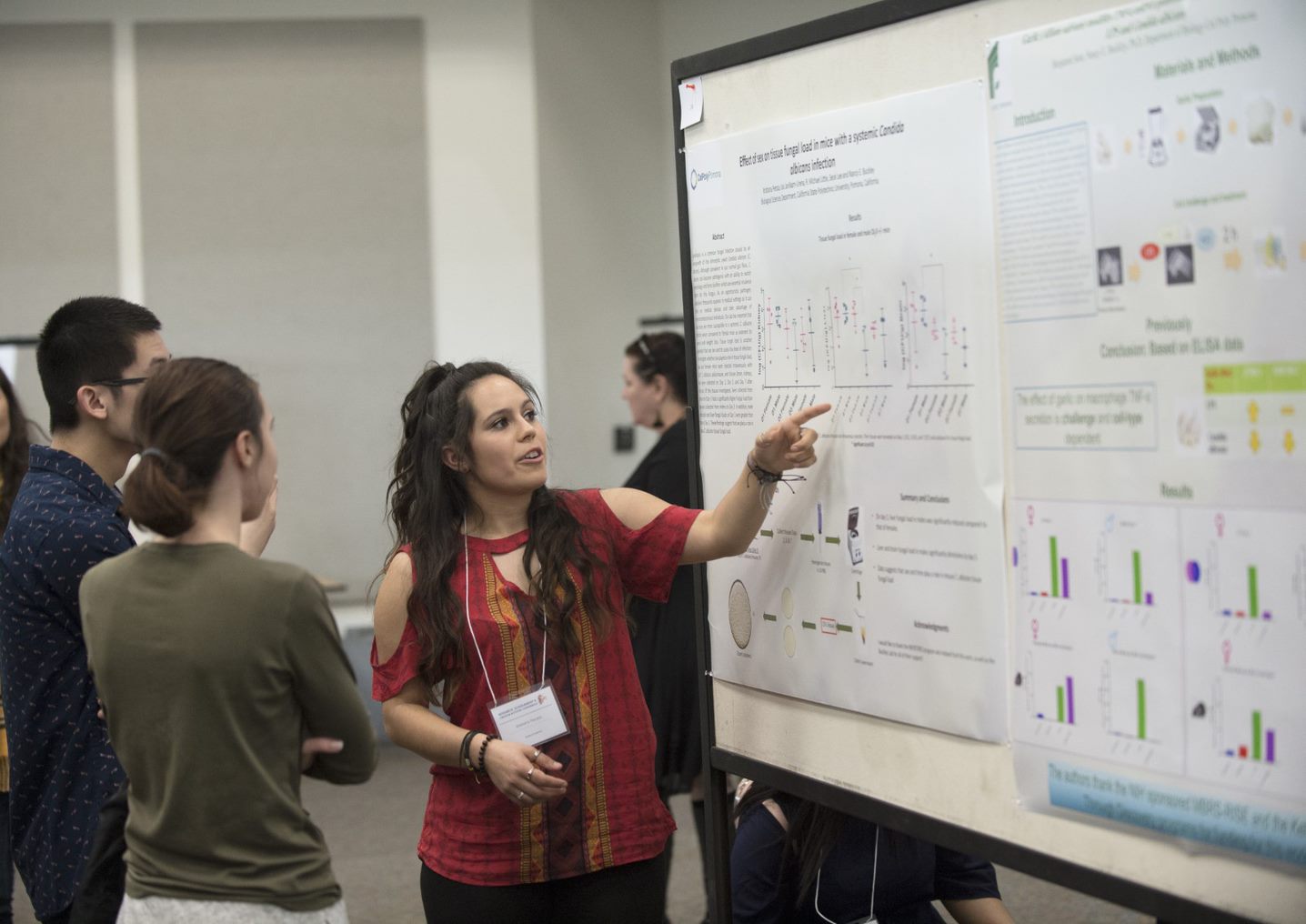 Two students standing in front of their poster presentation engaged in conversation with guests