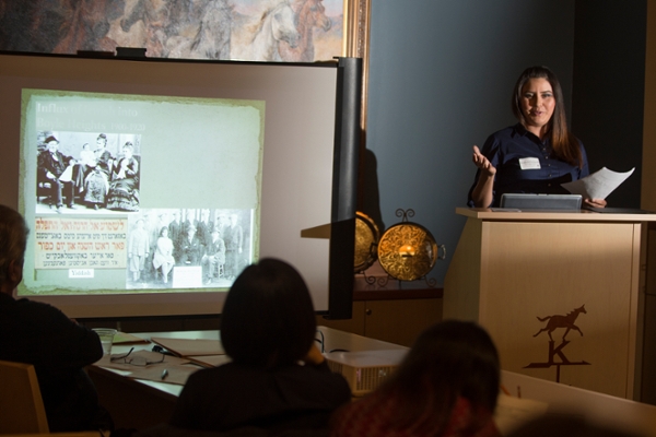 Student presenting research on a podium and next to a projected screen in front of an audience