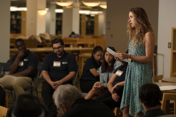 Student in blue dress reciting poetry to audience