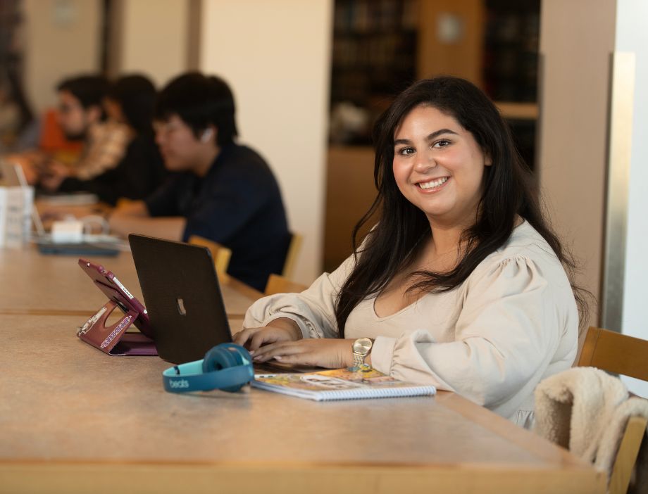 Student smiling with her laptop open.