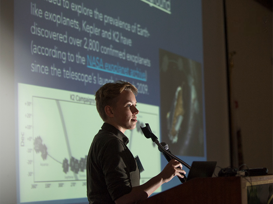 Student presenting his research at a podium.