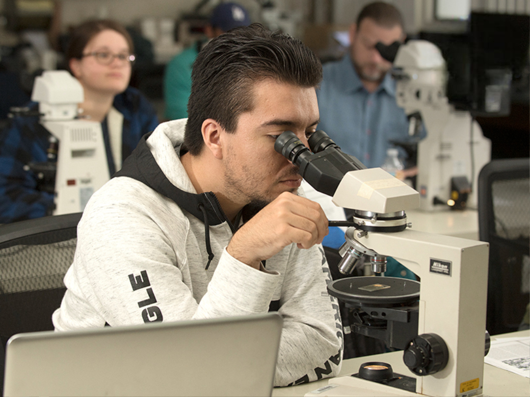 Student looking through a microscope.