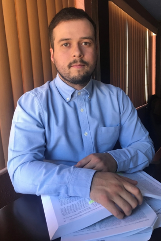 Student in a blue shirt sitting down and holding books