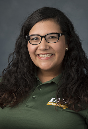 female student wearing a green staff polo and posing