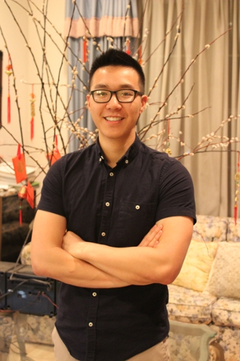 Male student in a well decorated room crossing arms and confidently posing 