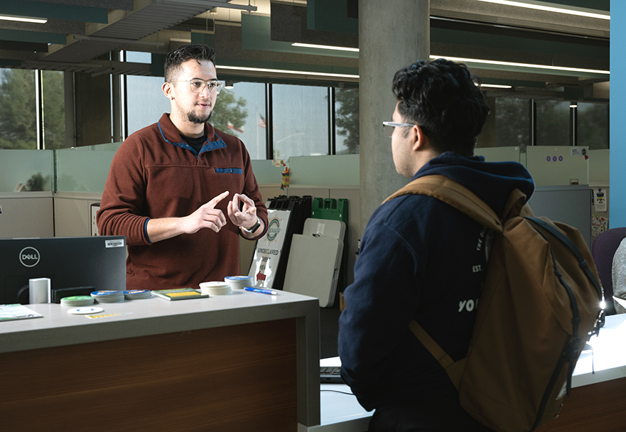 Image of a woman providing help to a student across a desk