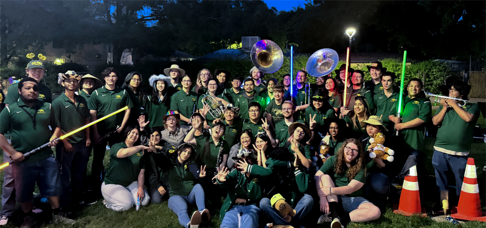 Pep band members standing on grass in the evening