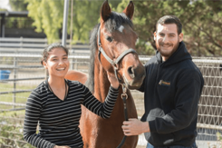 Two students outdoors with a horse