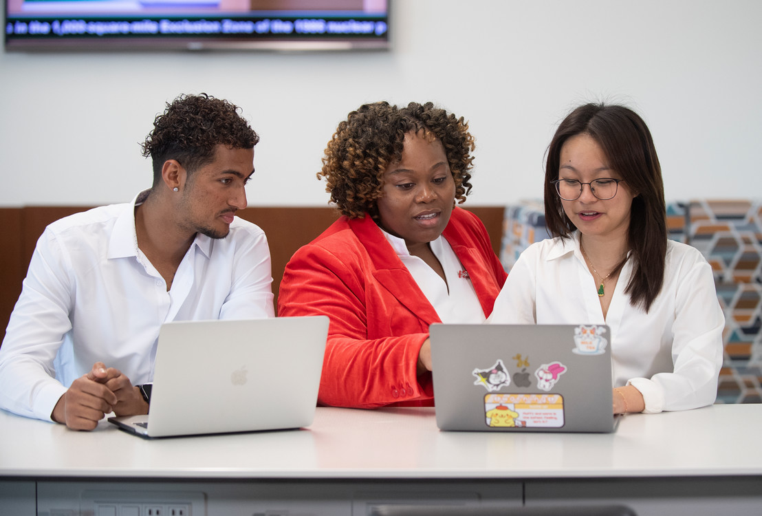 student showing computer to peers