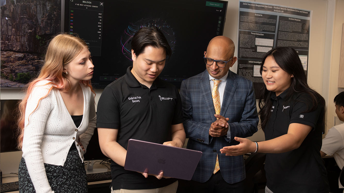 Dean with students in the data center looking at laptop