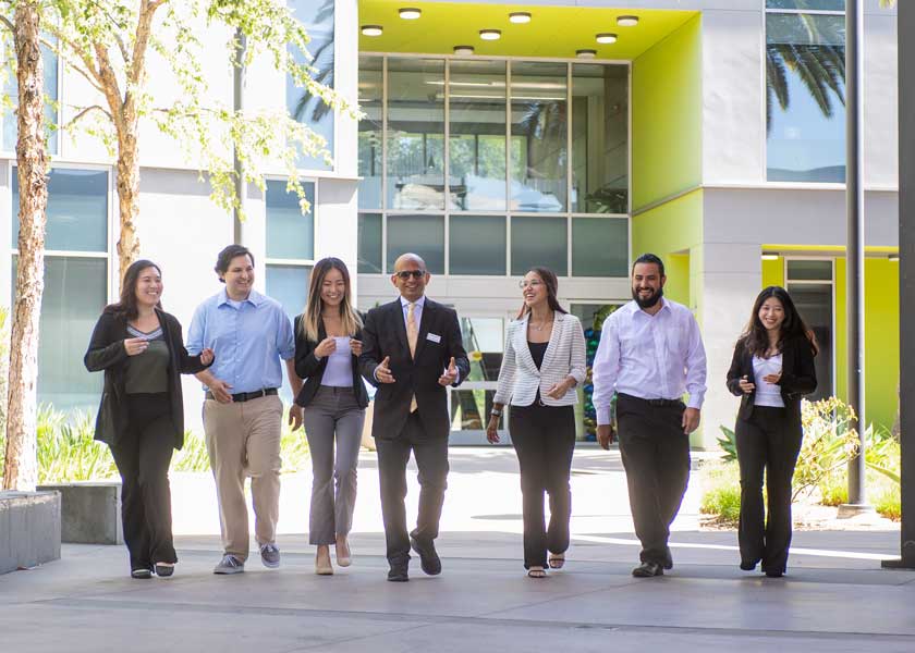 Dean Krishnamurthy walking through CBA courtyard with grad students