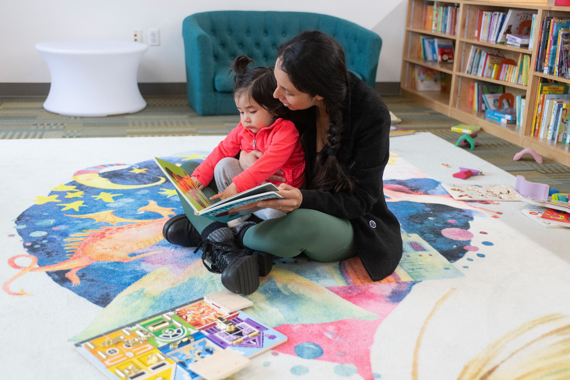 a student reading to a child on her lap