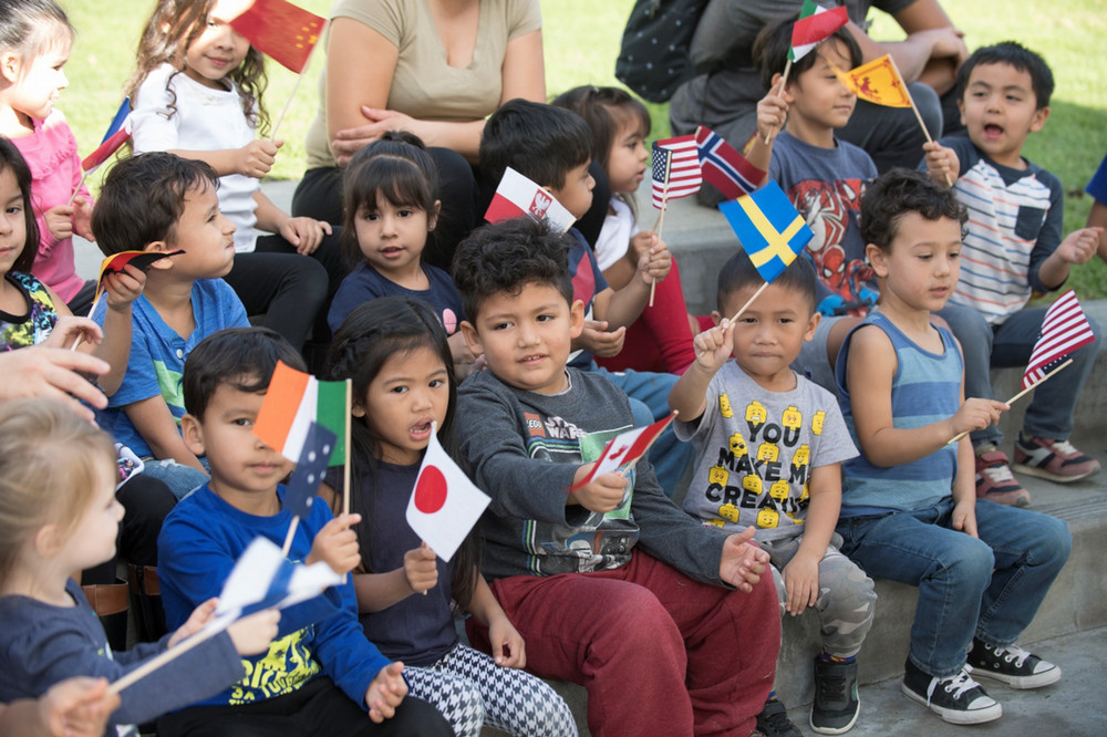 Young children wave small flags of different countries