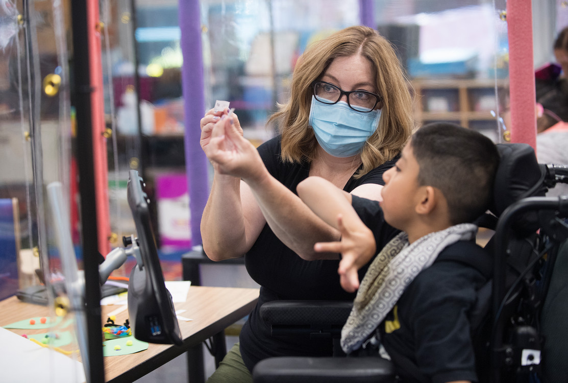 A special ed teacher works with a child on an art project.