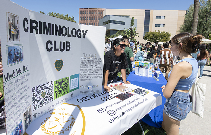 Student leader speaks to a peer at Criminology Club booth at the 2023 Resource Fair